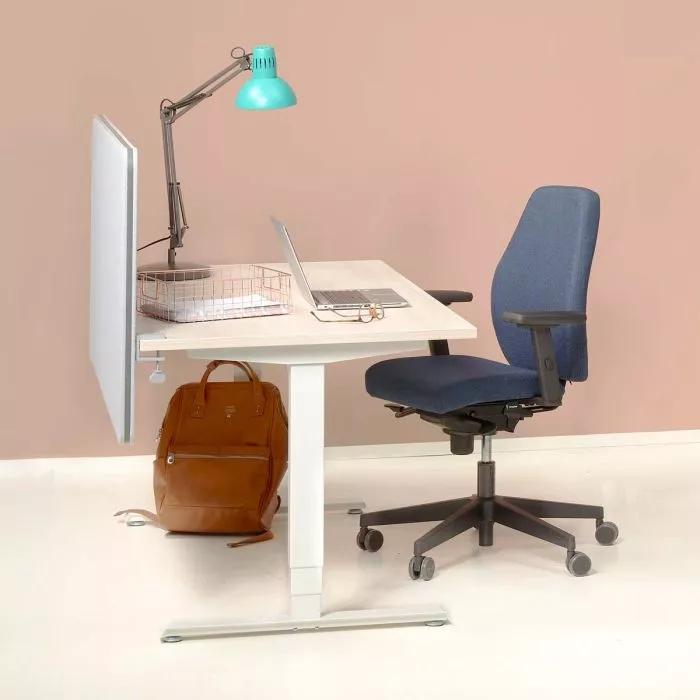 A tidy desk setup with a white pedestal table, blue ergonomic chair, teal adjustable lamp, laptop, wire document basket, and a brown backpack on the floor beside the wall.